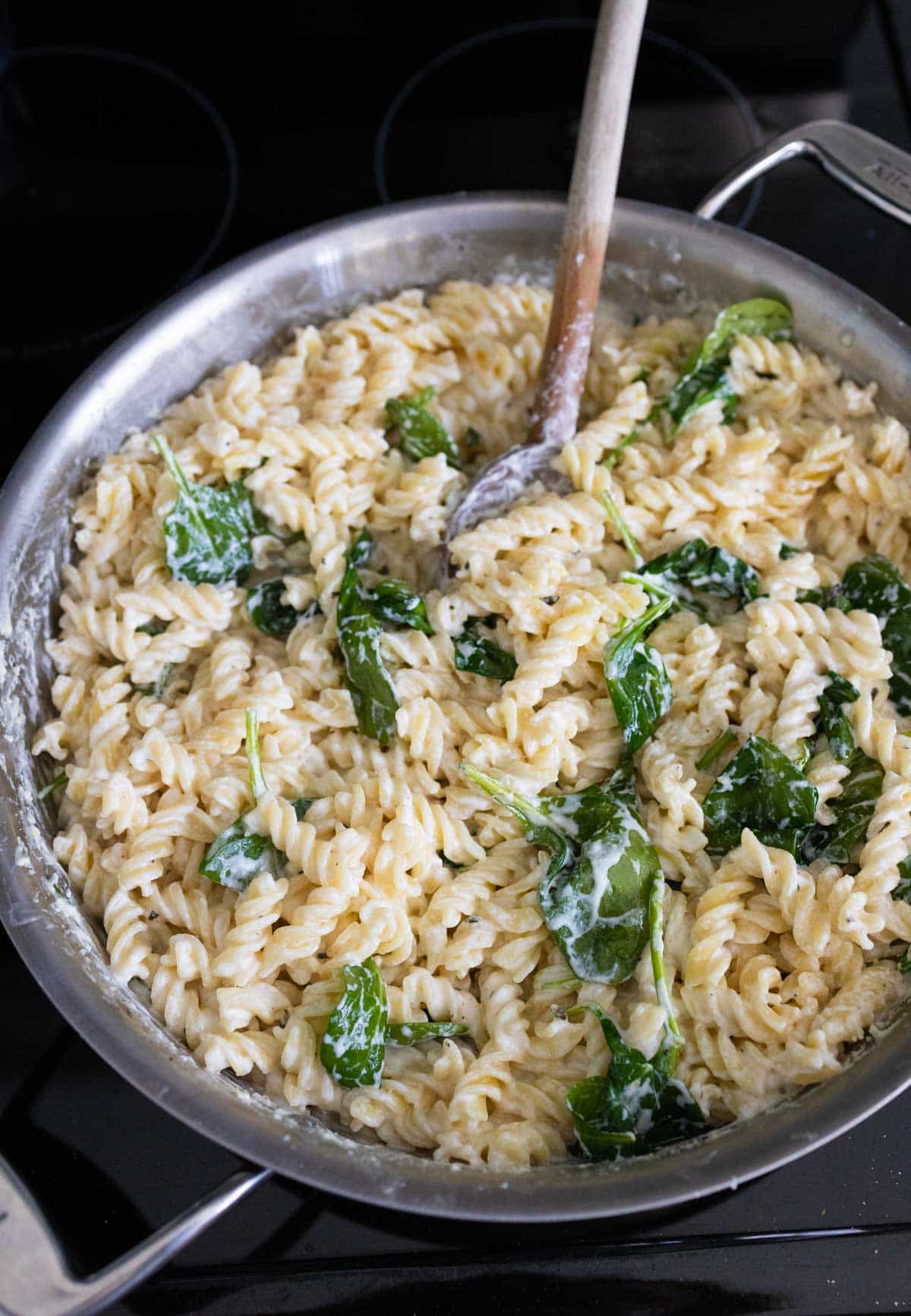 The spinach has been wilted and stirred into the pasta skillet.