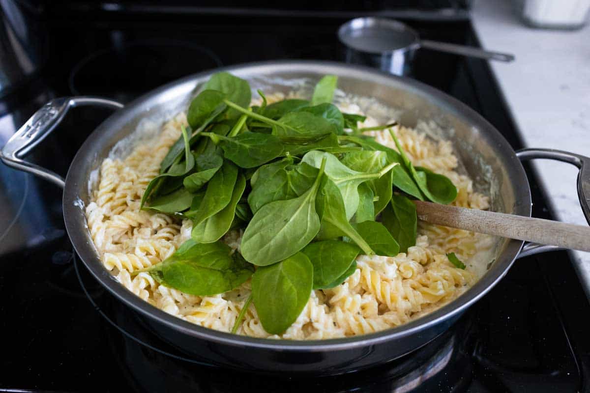 The pasta and baby spinach have been added to the sauce.