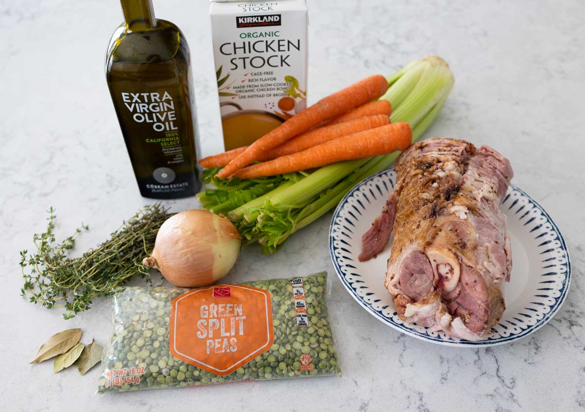 The ham bone, fresh carrots, and dried peas are on the counter with the rest of the ingredients.