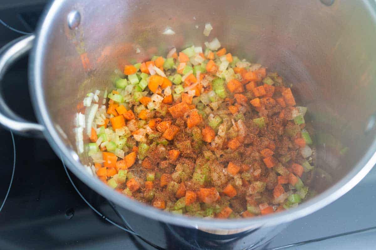 The soup pot has the cooked carrots topped with seasoning.