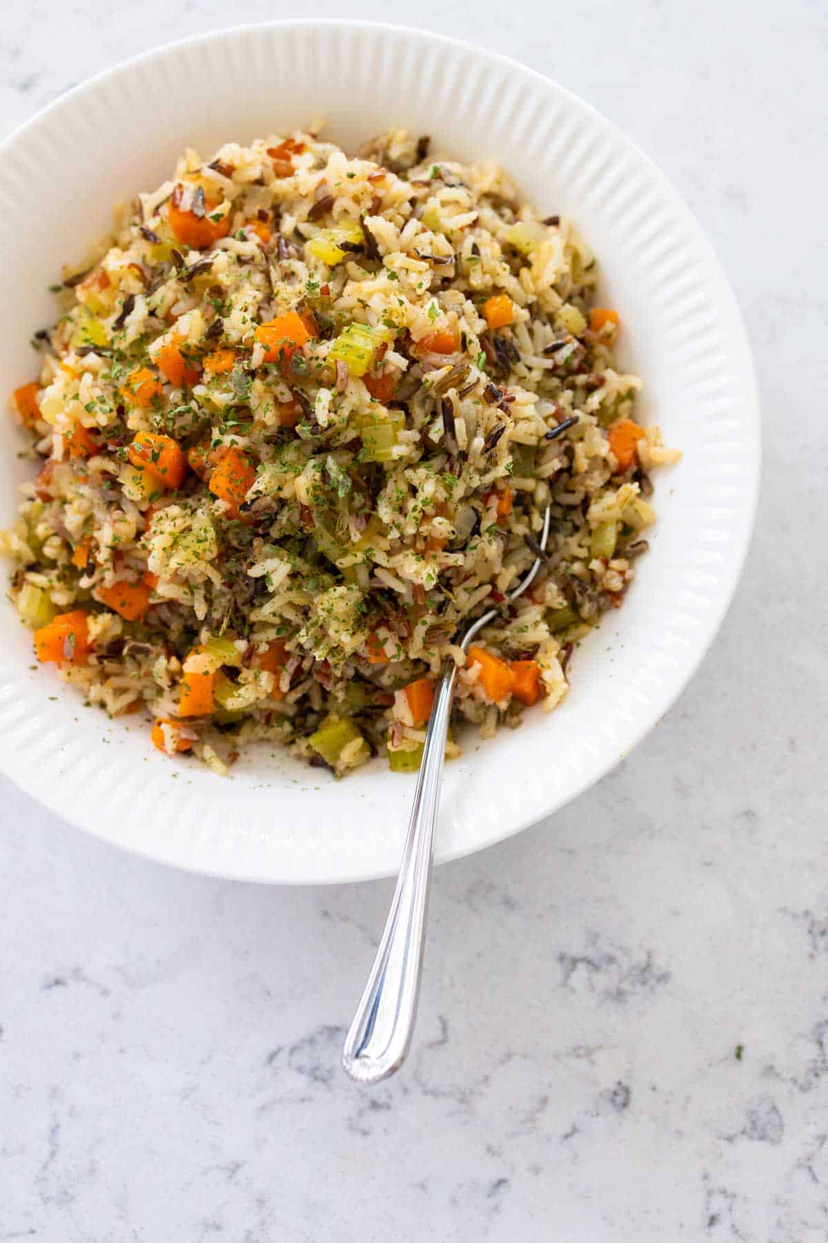 The finished pilaf is in a white bowl with a spoon.