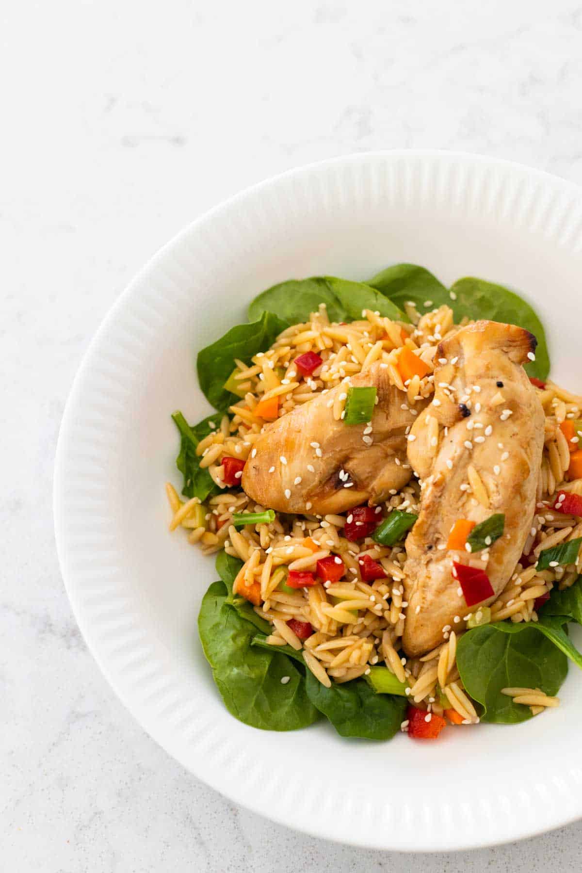 A white bowl has a serving of the prepped Asian chicken pasta salad.