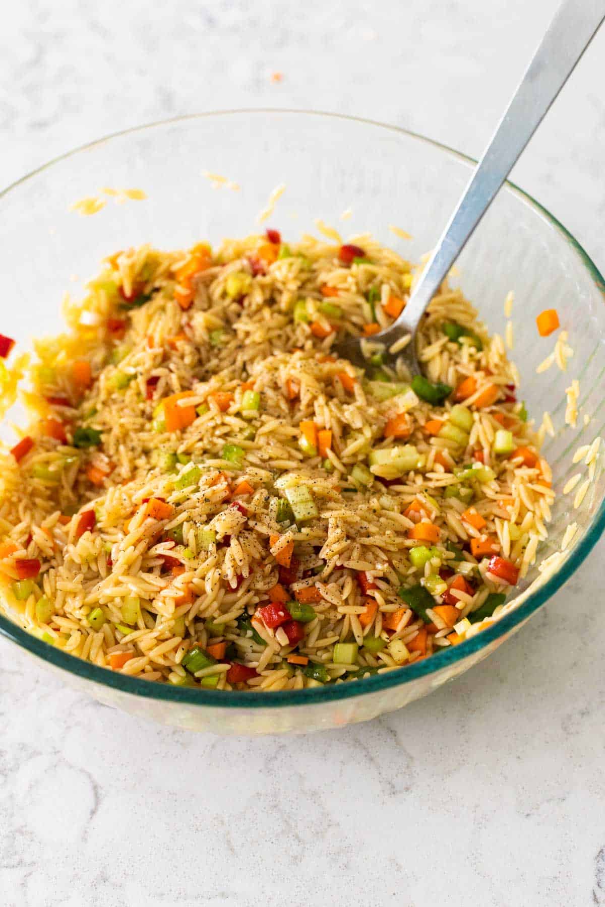 The remaining half of the dressing has been poured over the pasta and the salad has been mixed together.
