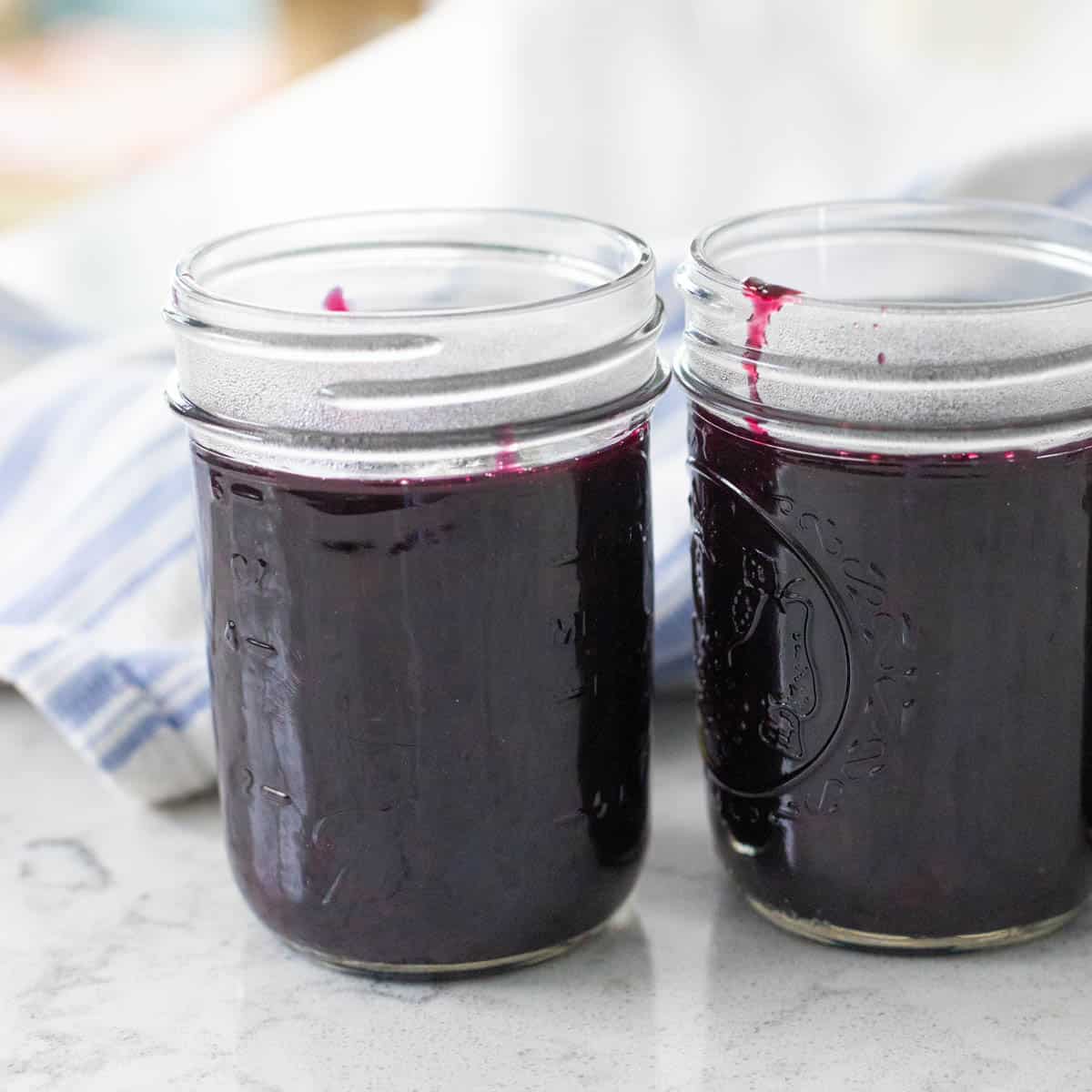 Two small jelly jars have been filled with the finished blueberry jam.