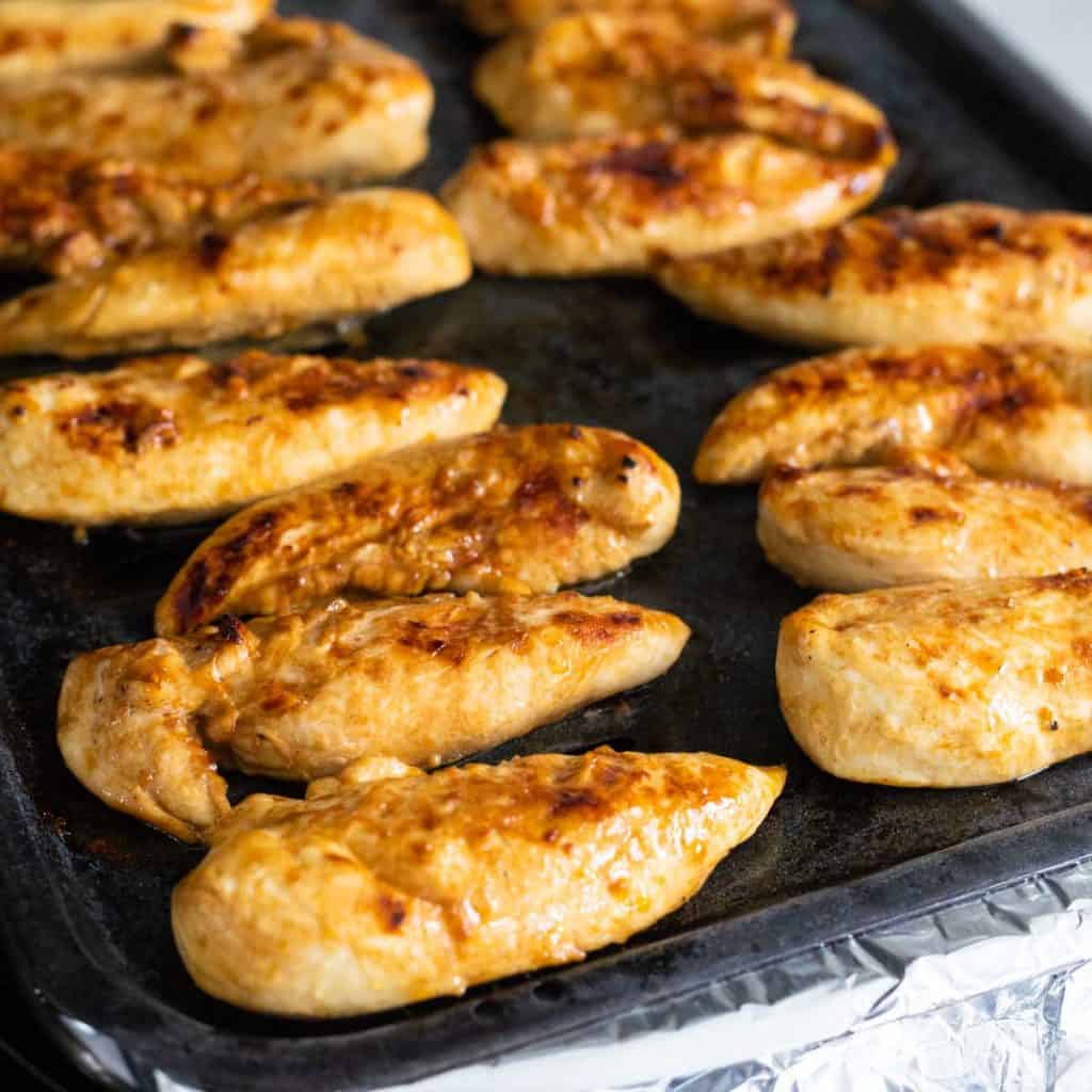 A broiler pan of chicken tenderloins.