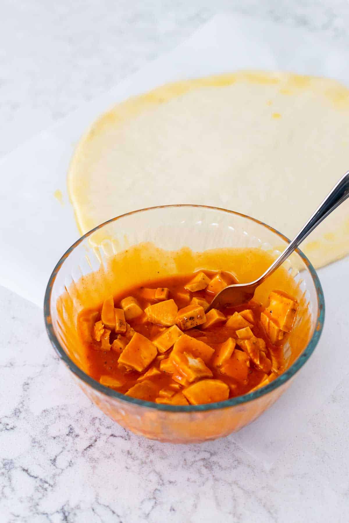 The mixing bowl has chunks of chicken tossed with buffalo sauce.