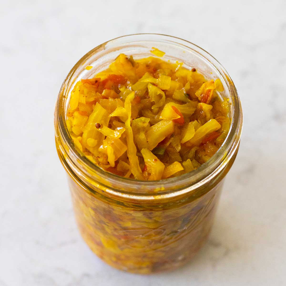 A mason jar is filled with the finished chow chow relish.