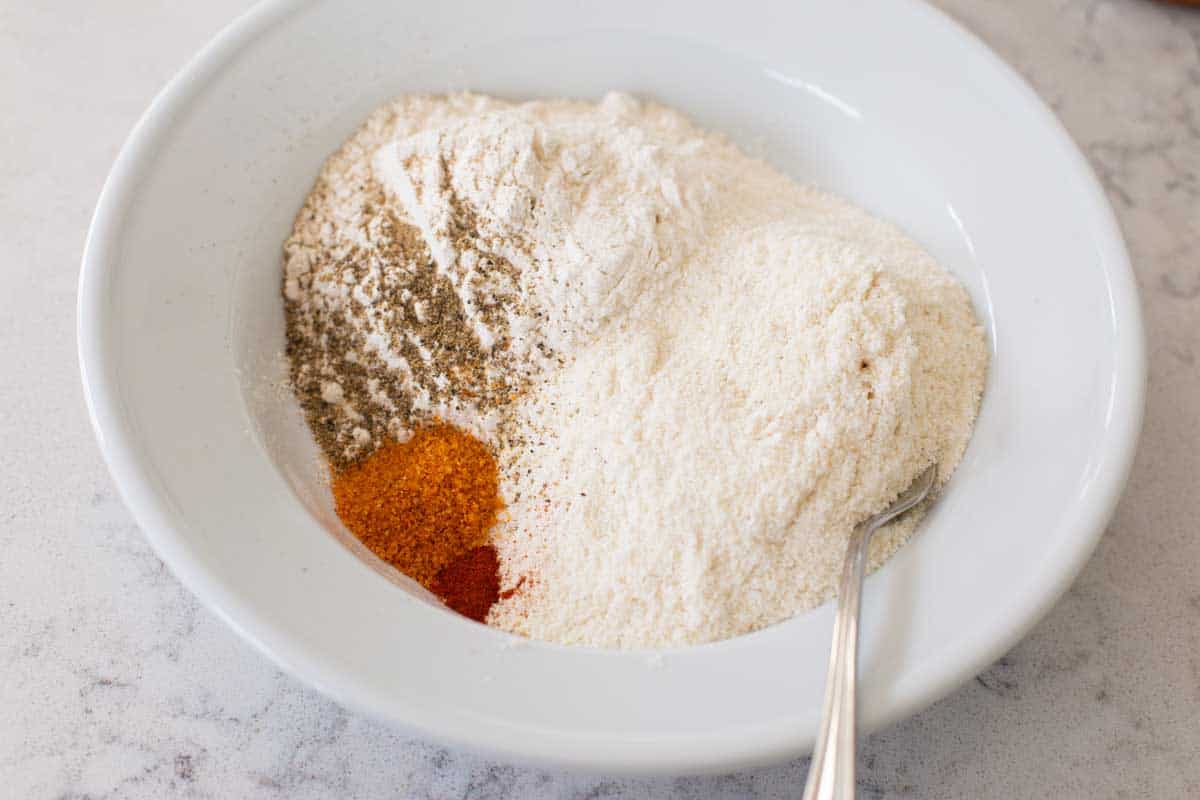 A mixing bowl has the cornmeal and seasonings for the fried green tomato batter.