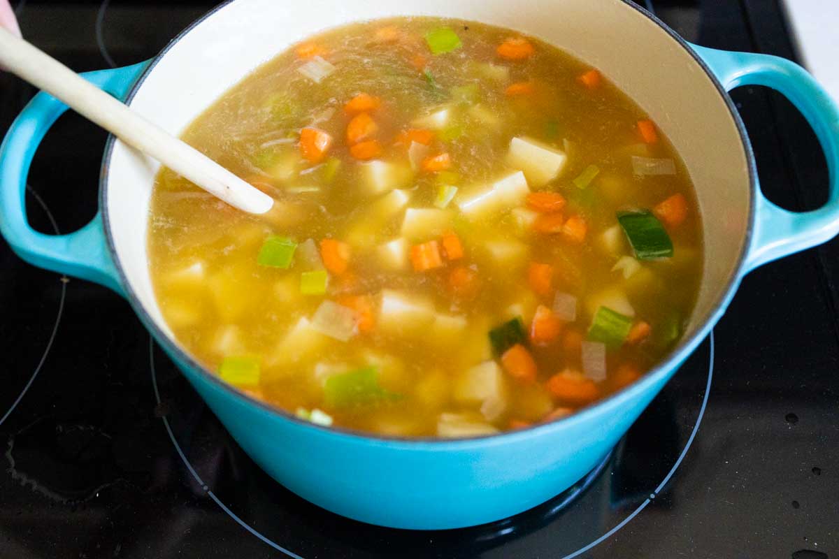The broth is poured into the soup in the pot.