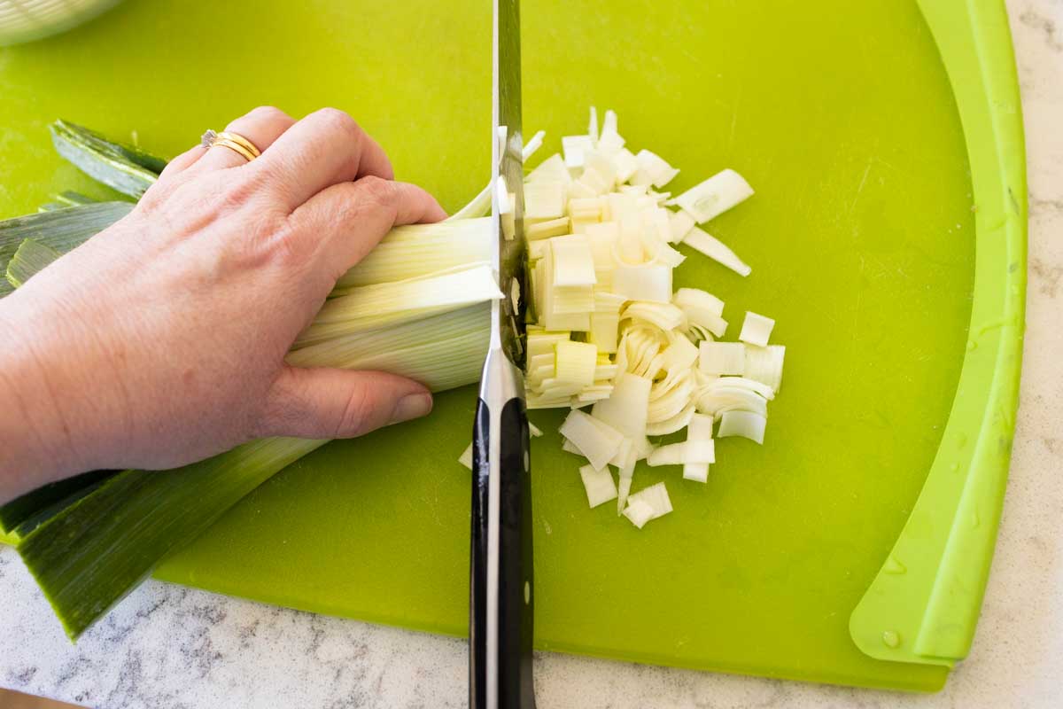 The leek strips are now being chopped into small pieces with a chef knife.