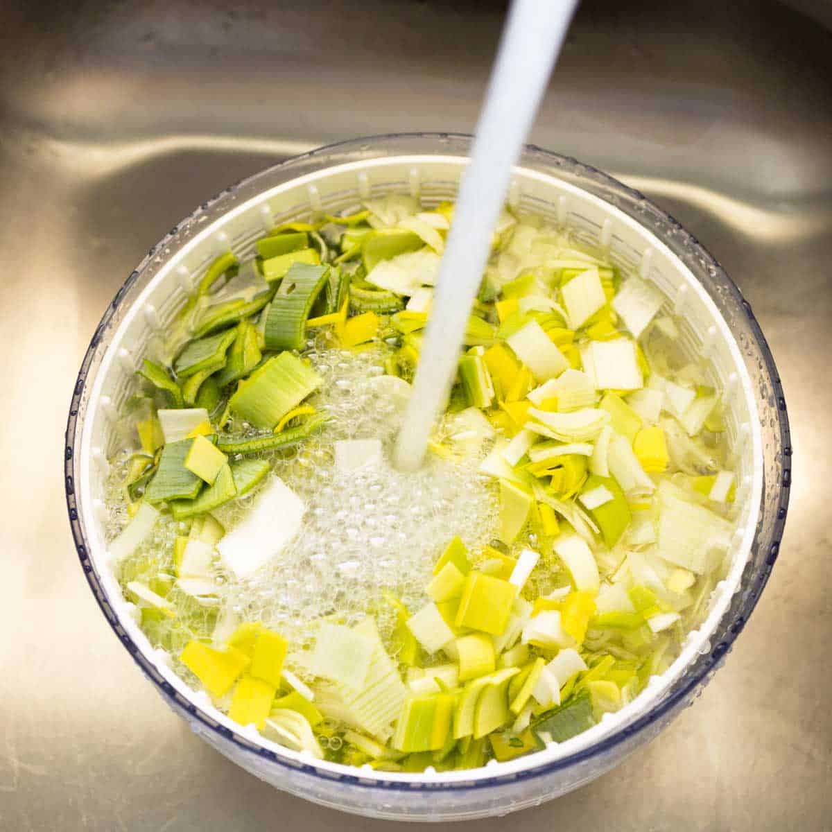 The chopped leeks are in a salad spinner being rinsed.