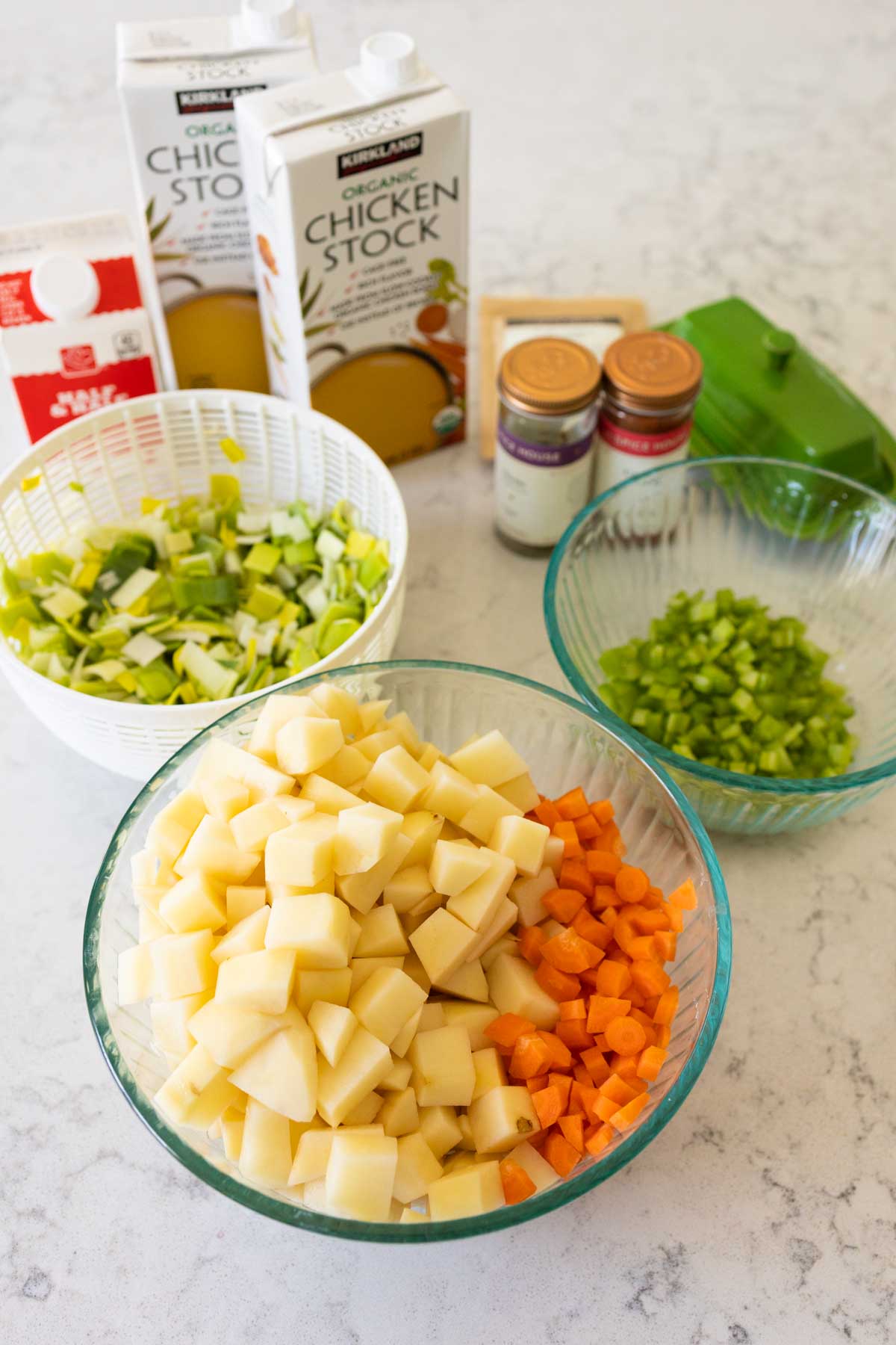 Bowls filled with chopped potatoes, carrots, leeks, and celery are sitting on the counter to show the scale.