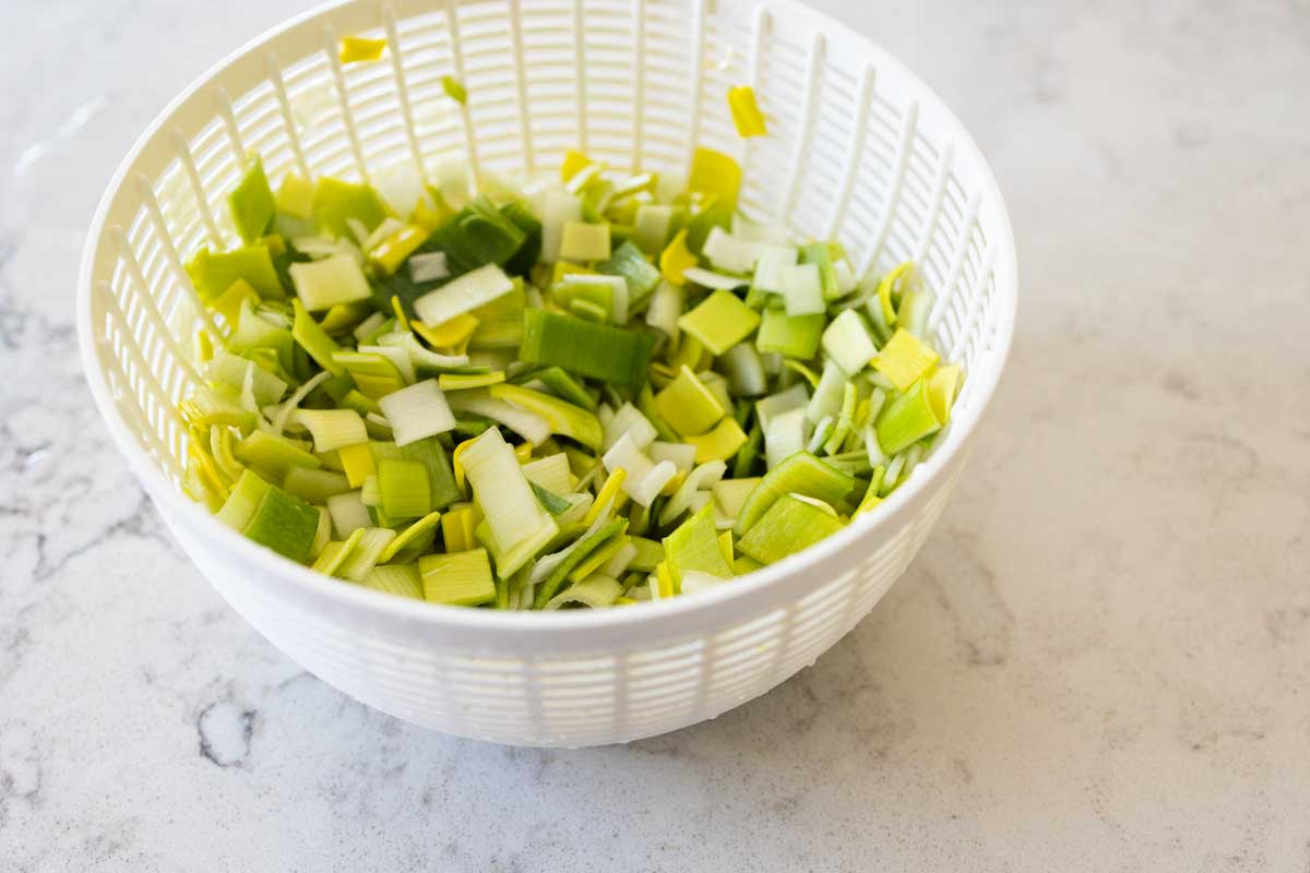 The clean leeks are now in the white spinner basket insert of the salad spinner.
