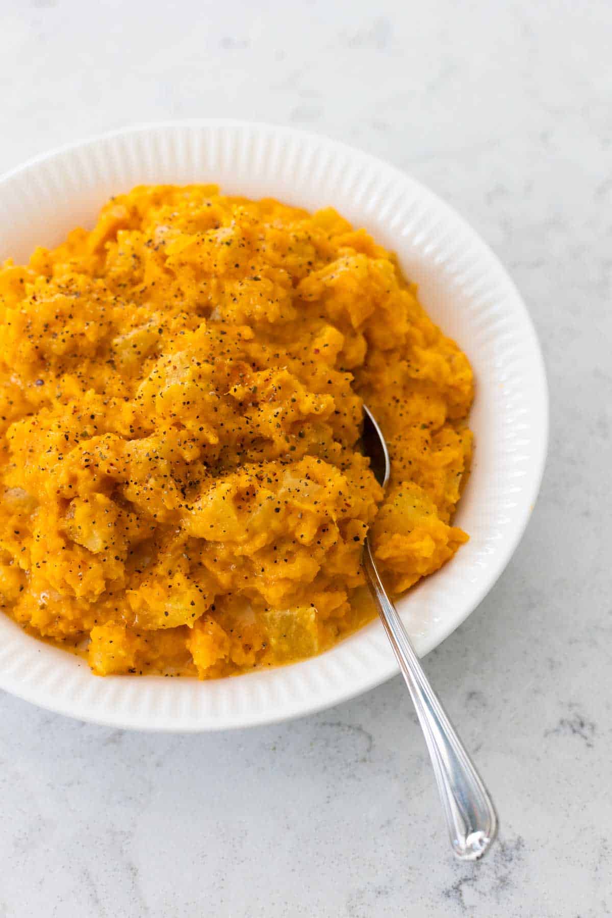 The casserole has been mashed and is now in a serving bowl with a spoon.