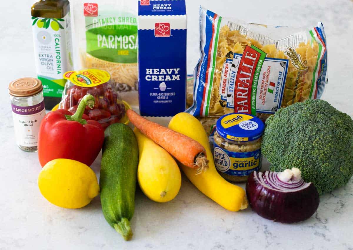 The fresh vegetables and farfalle pasta are on the counter.