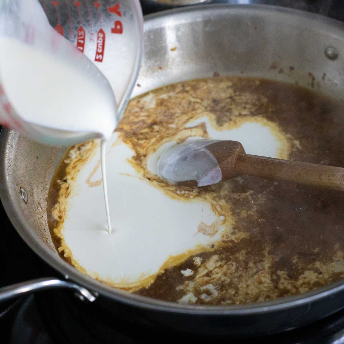 The cream is being poured into the sauce.