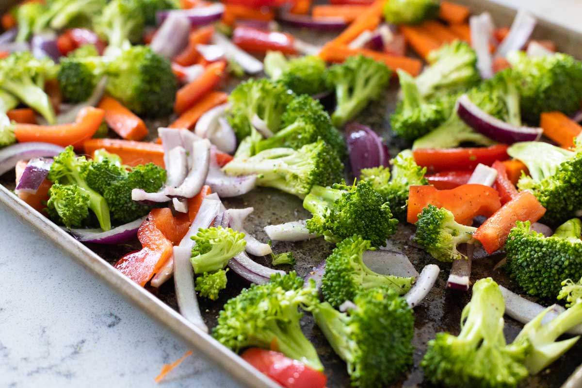 The baking sheet shows the prepped broccoli, onions, carrots, and peppers.