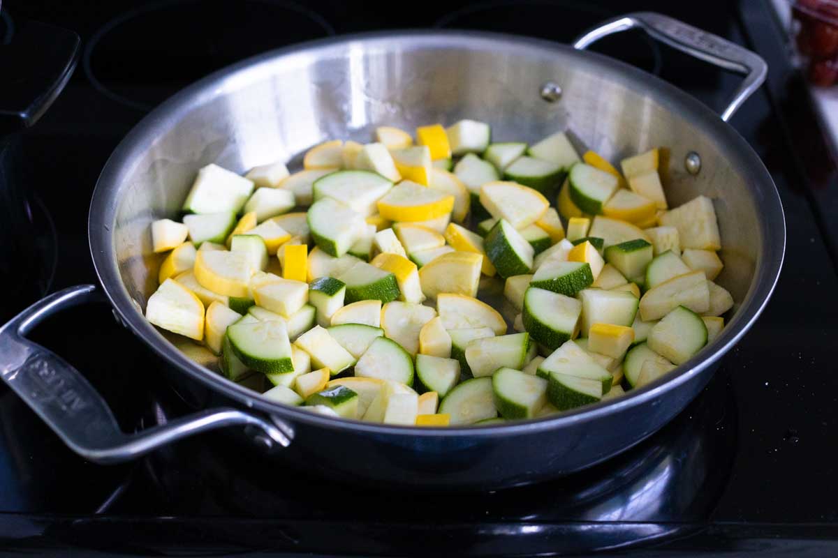 The squash and zucchini are being cooked in the skillet.