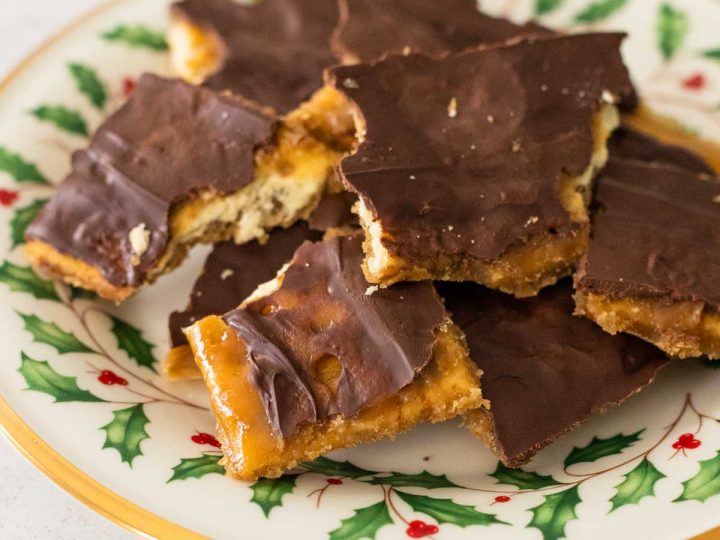 A Christmas holly plate has a pile of choclolate covered saltine cracker toffee.