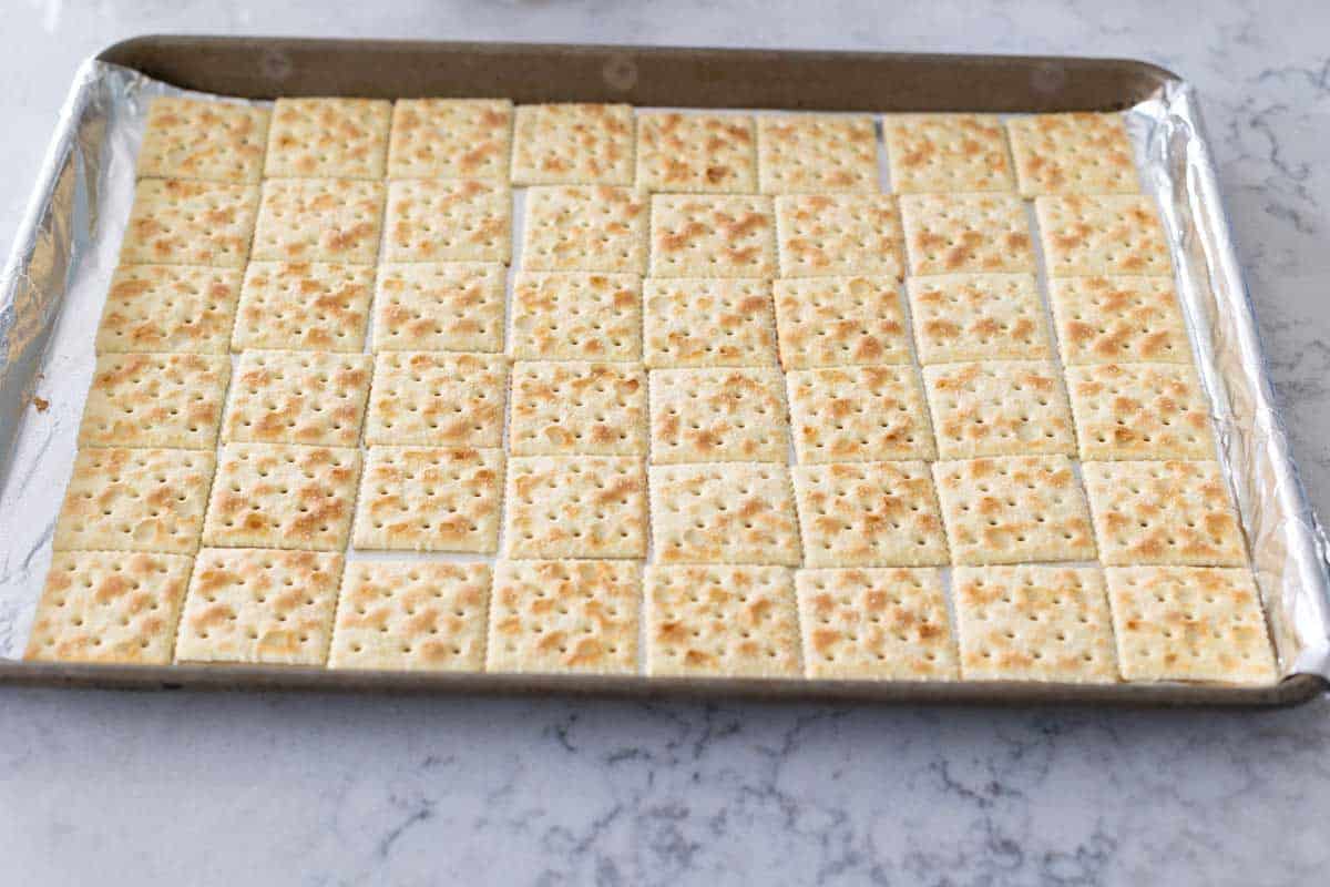 The baking pan has a perfectly even layer of saltine crackers in neat rows.