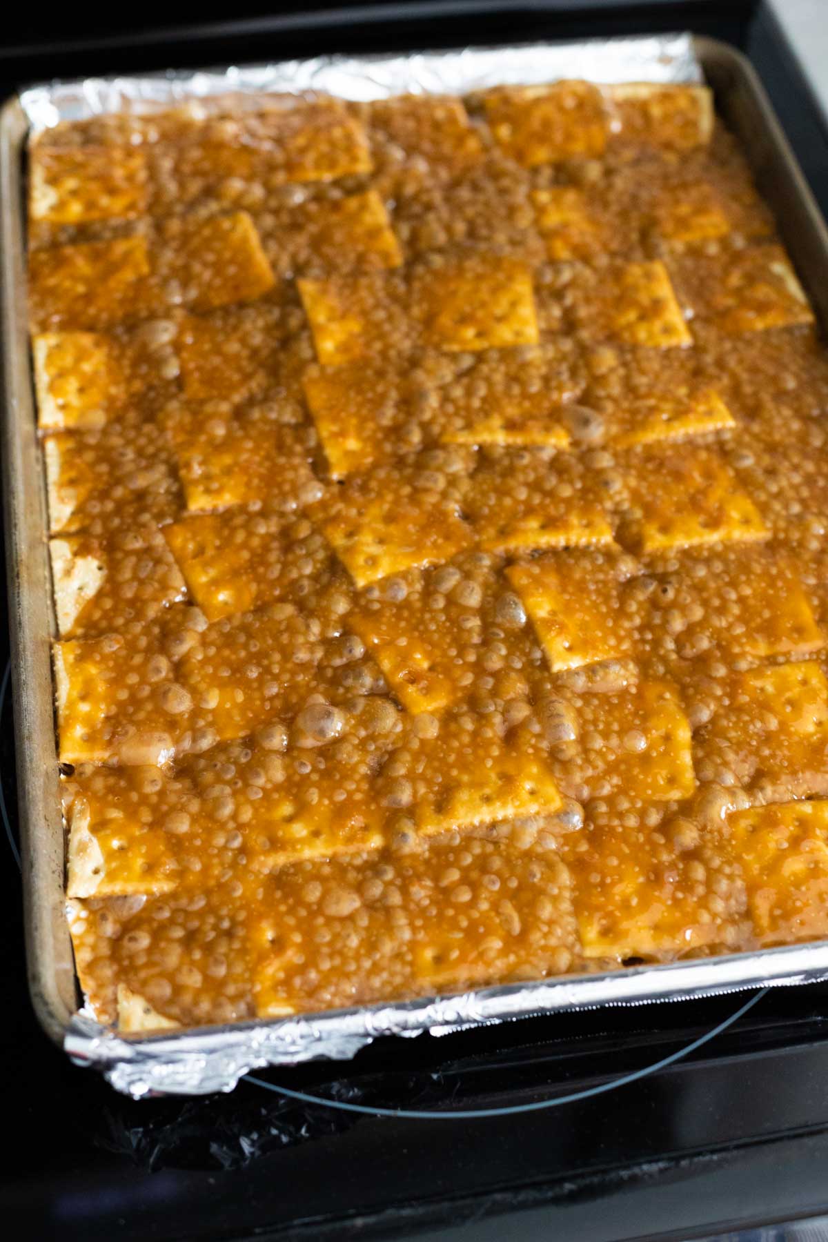 The pan of saltine crackers with toffee sauce have been baked and you can see the sugar has boiled up into bubbles.