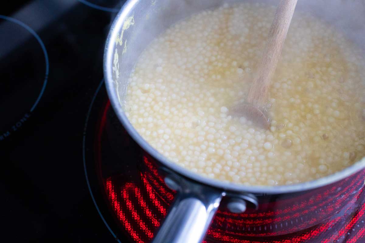 The couscous is almost finished cooking and the liquid has been mostly absorbed.