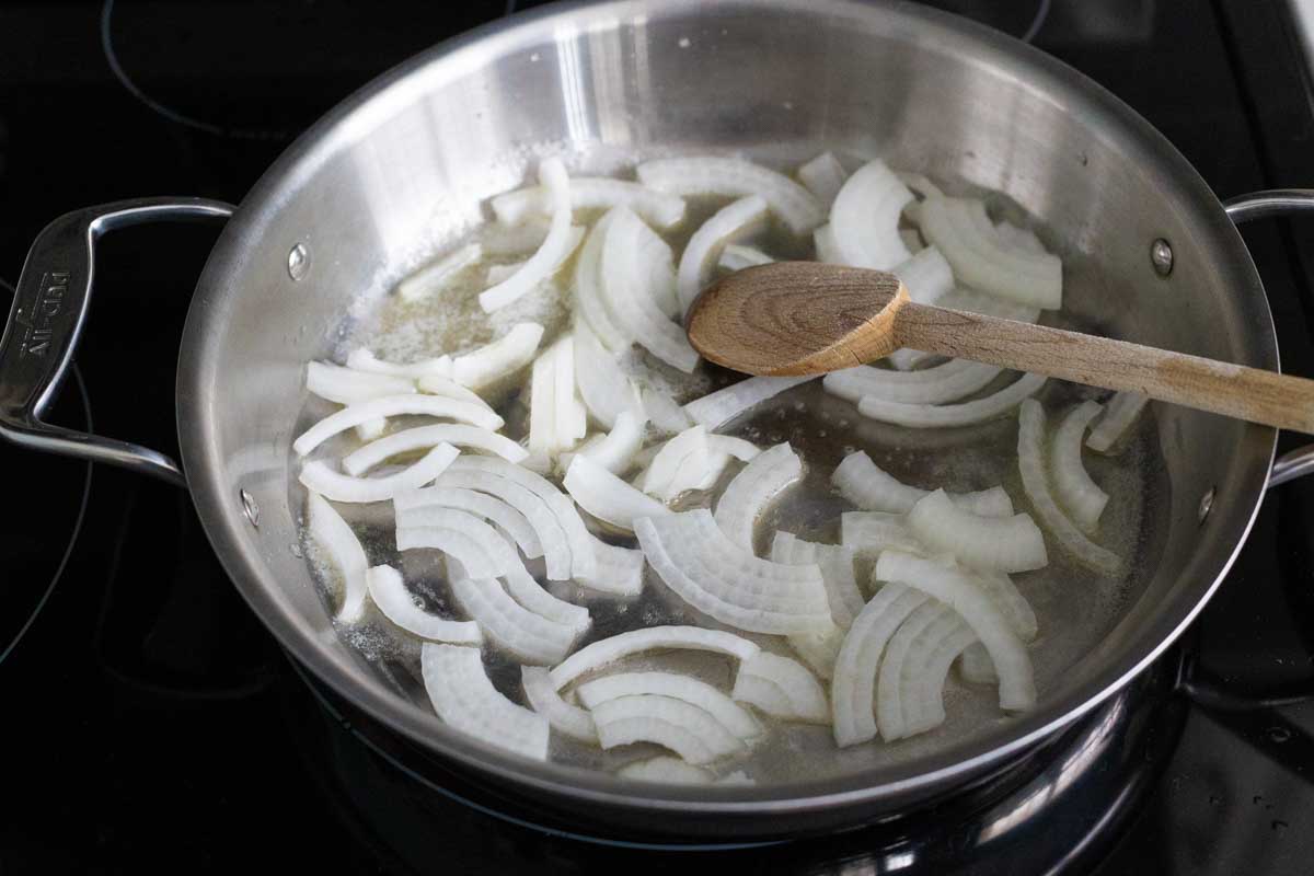 The sliced onion is cooking in melted butter in a deep skillet.