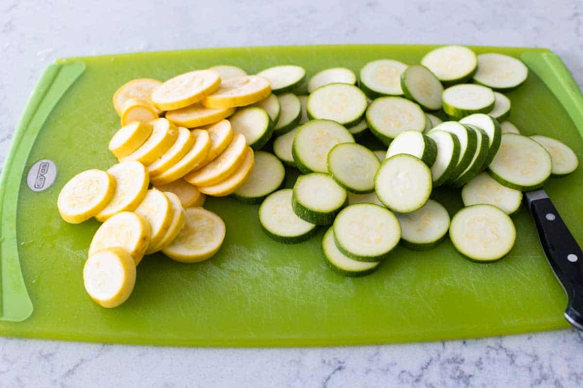 The yellow squash and zucchini have been sliced into 1/4-inch thick slices.