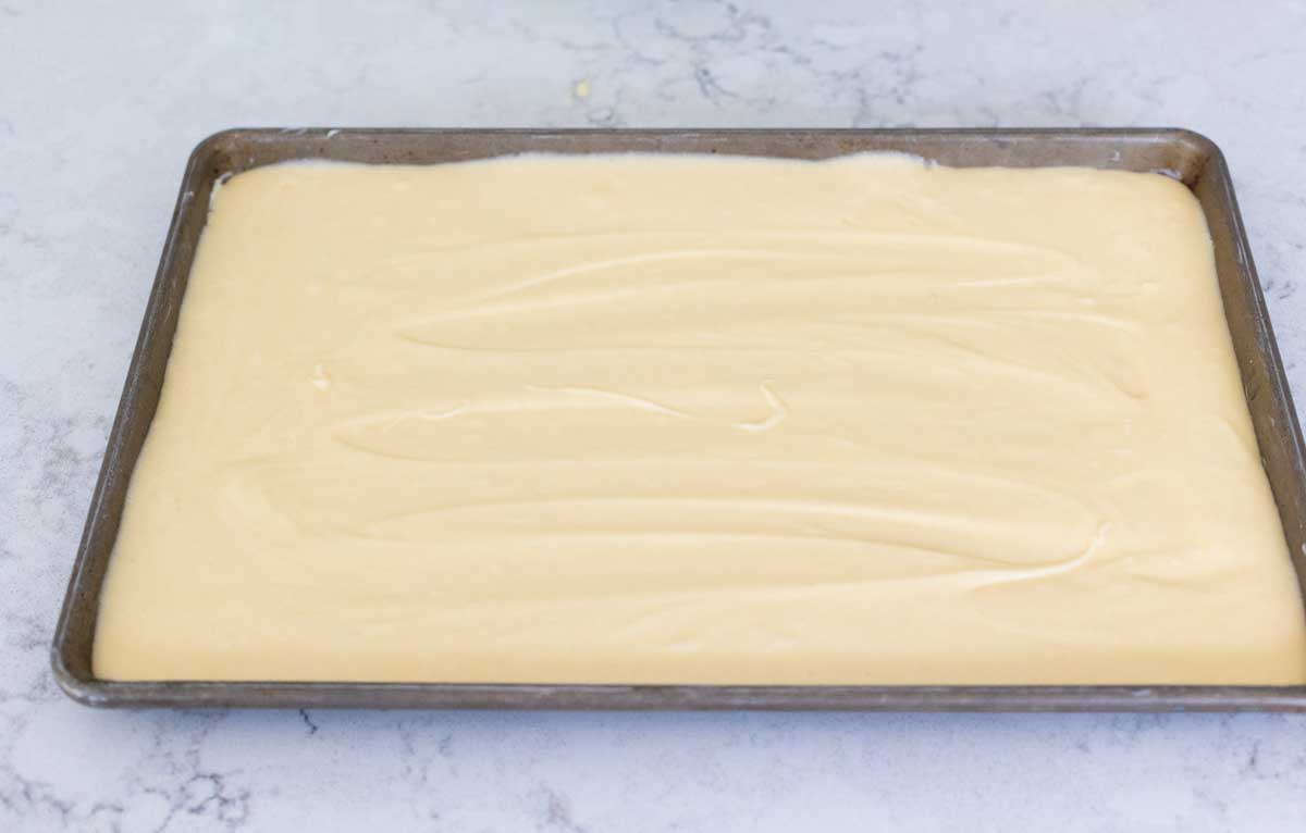 The cake batter has been spread into an even layer in a baking pan with a rim.