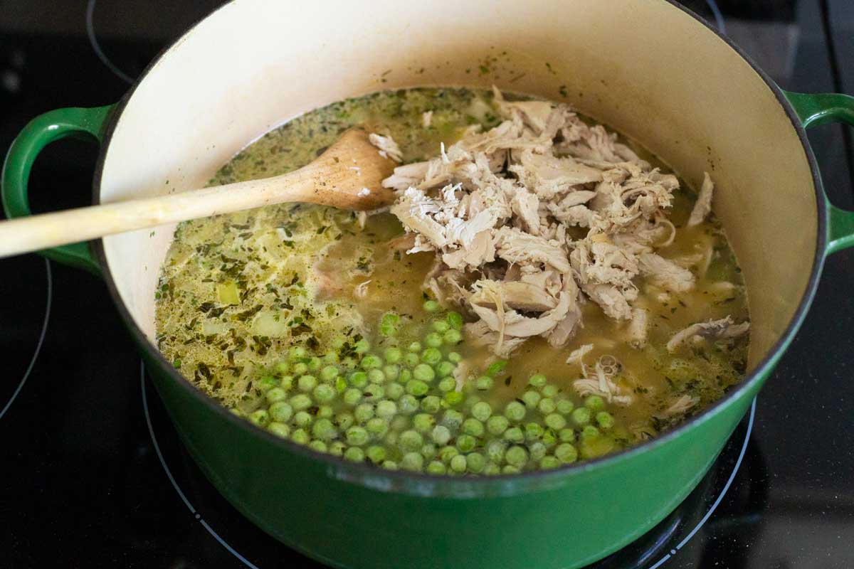 The shredded chicken and frozen peas have been added to the soup.