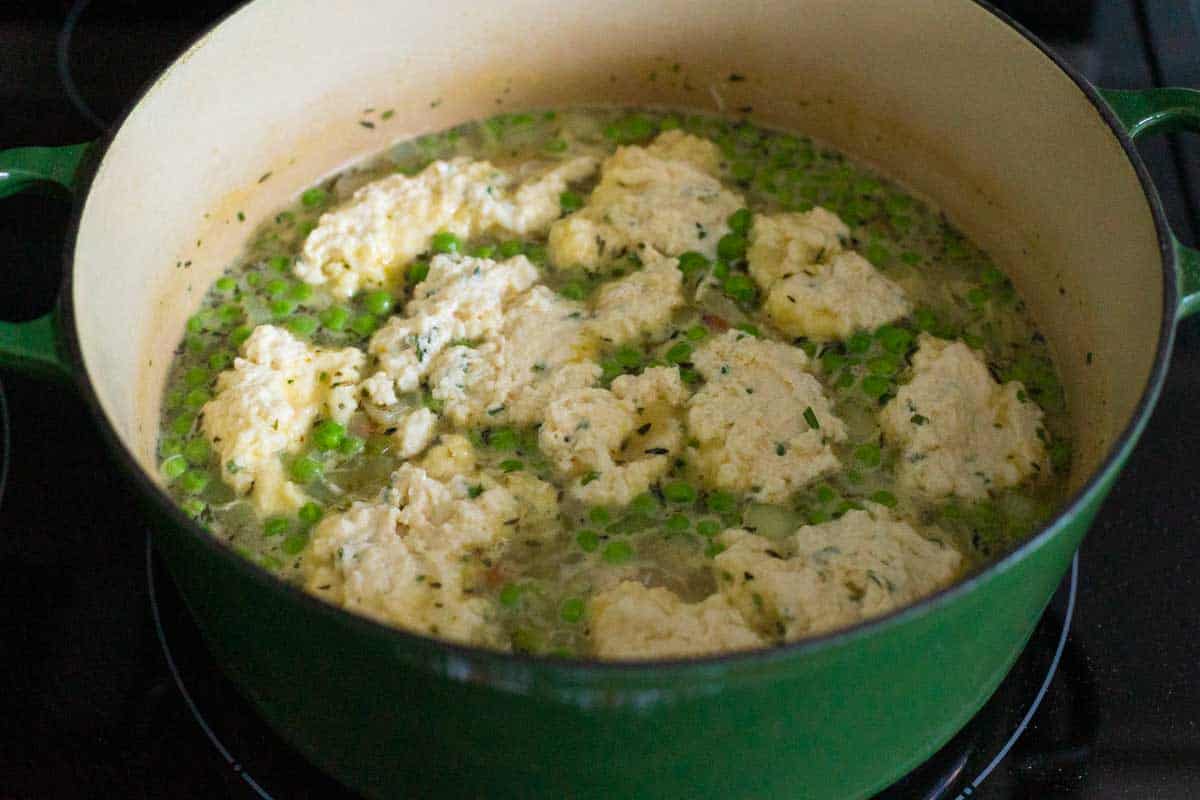 The dumpling dough has been spooned into the broth in the Dutch Oven.