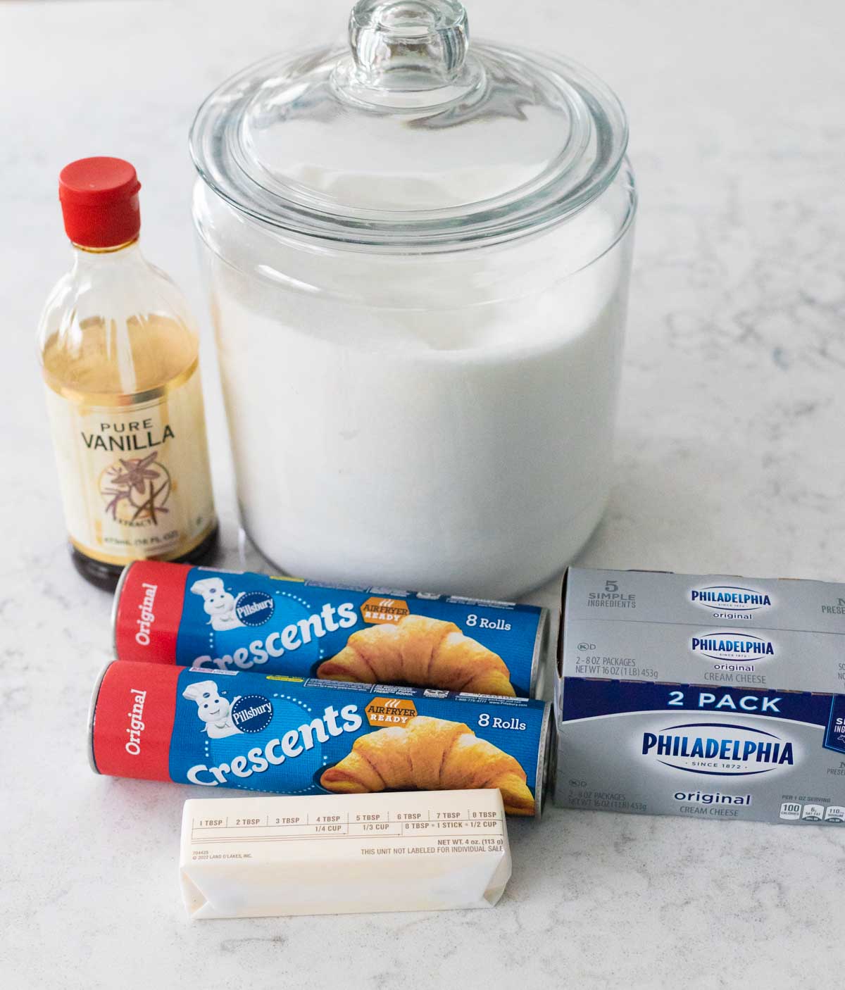 The crescent roll dough and cream cheese are on the counter next to the rest of the ingredients to make the dessert.