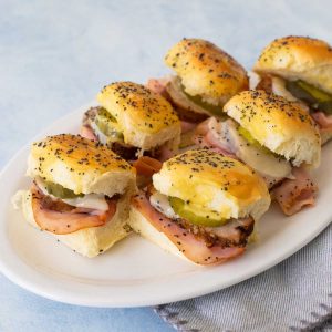 A white platter of mini slider sandwiches.