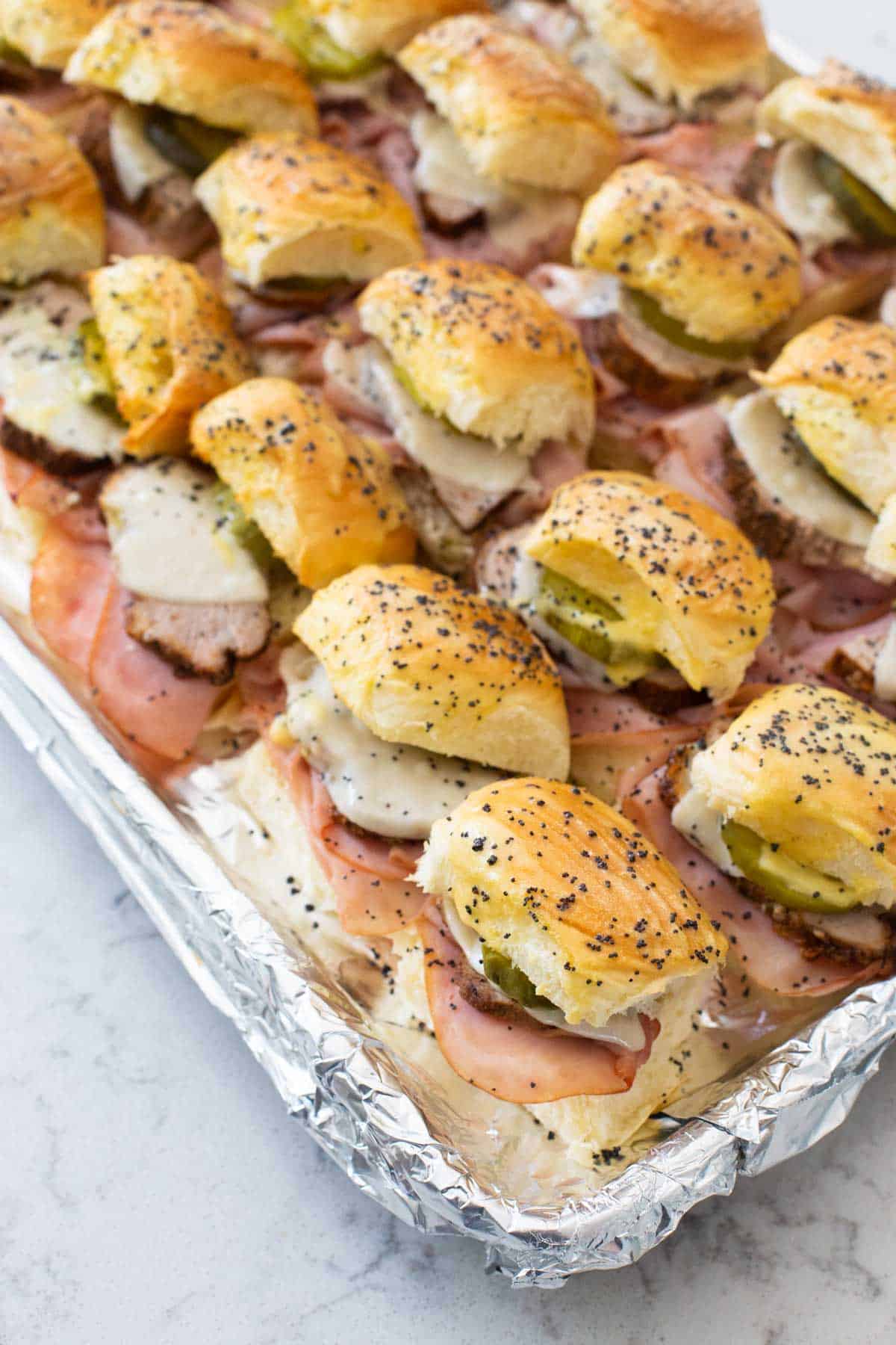 The slider sandwiches have been baked with poppy seeds on top.