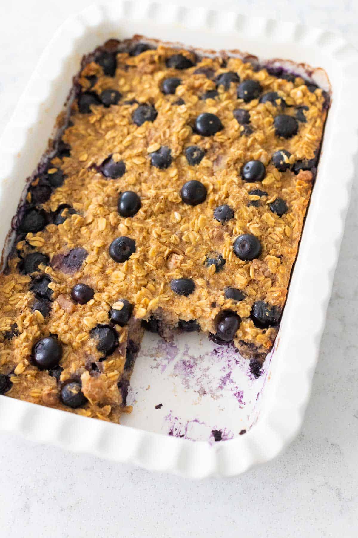 The baked oatmeal has been sliced and a square is removed from the pan.