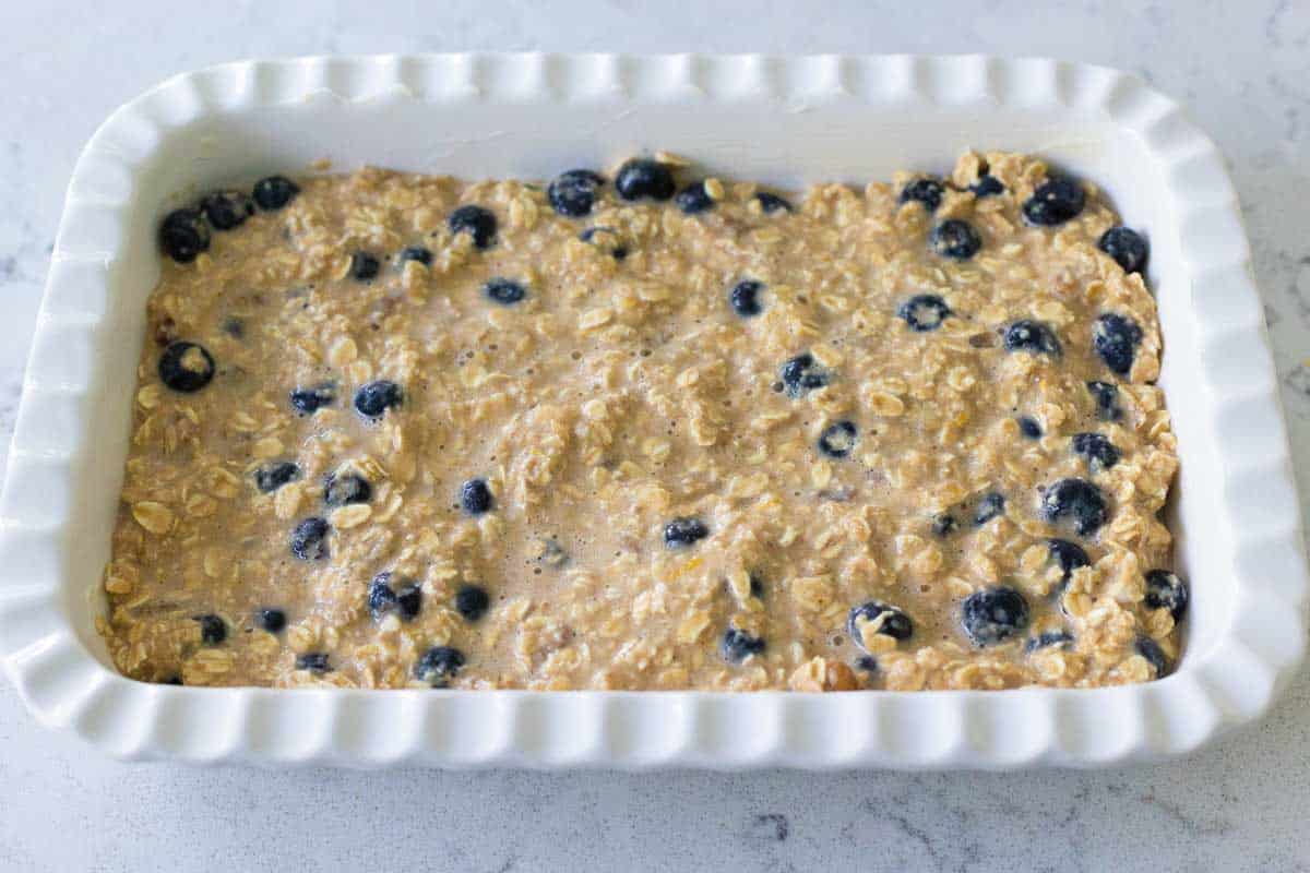 The oatmeal has been spread into an even layer in a white baking dish