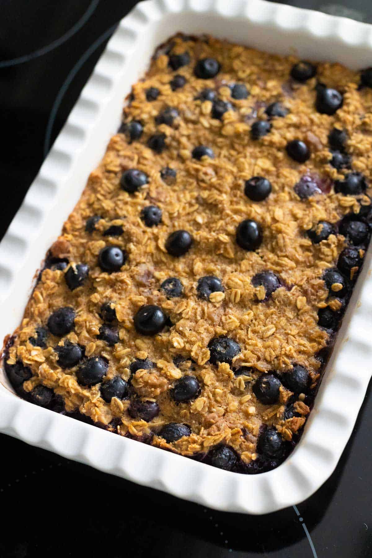 The baked oatmeal has just come out of the oven, the top is golden brown and the blueberries are shiny.