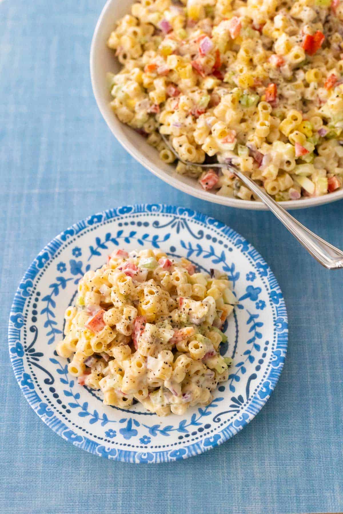 A scoop of the macaroni salad has been served on a small blue plate.