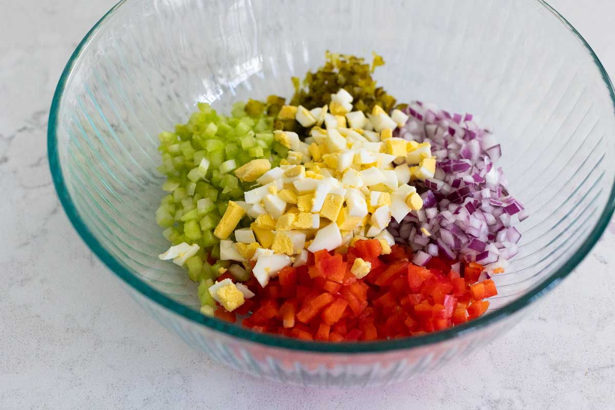 The mixing bowl shows how finely the red pepper, celery, red onion, hard boiled eggs, and gherkins have been diced.