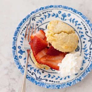 A classic strawberry shortcake has been split in half with fresh berries and whipped cream.