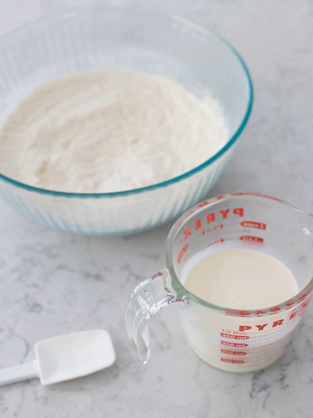 The mixing bowl has the dry ingredients and the measuring cup has the heavy cream.