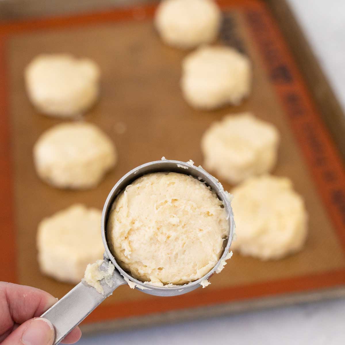 The measuring cup has been filled with dough to portion and shape the shortcakes.