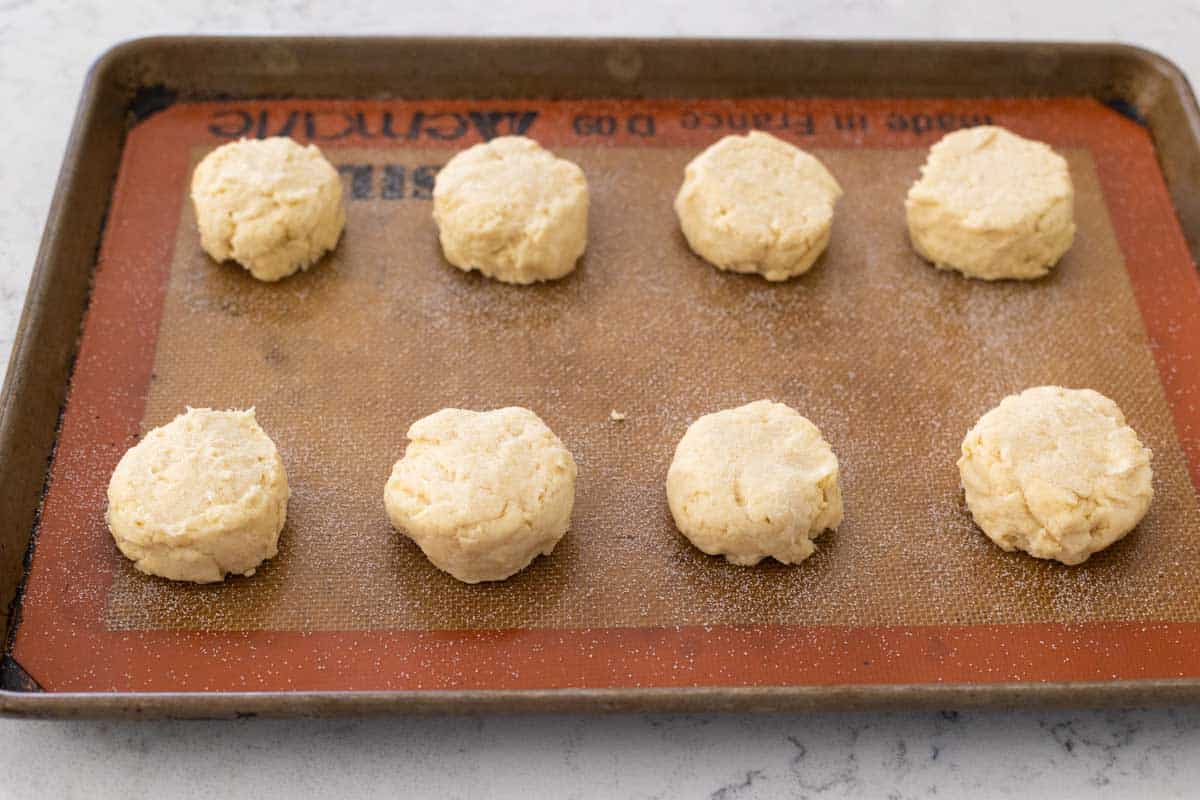 The shortcakes are in 2 rows of 4 on a baking sheet and have been sprinkled with sugar.