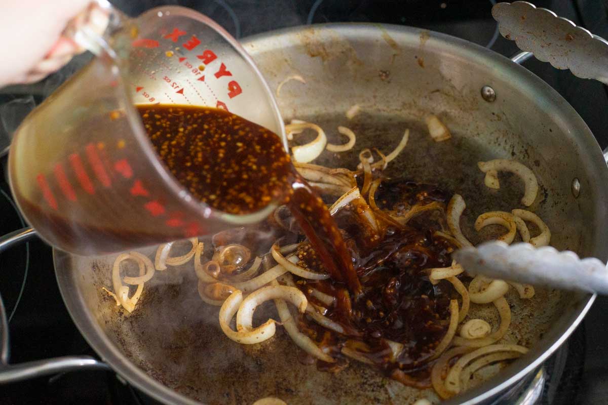 The sauce is poured into the skillet with the onions.