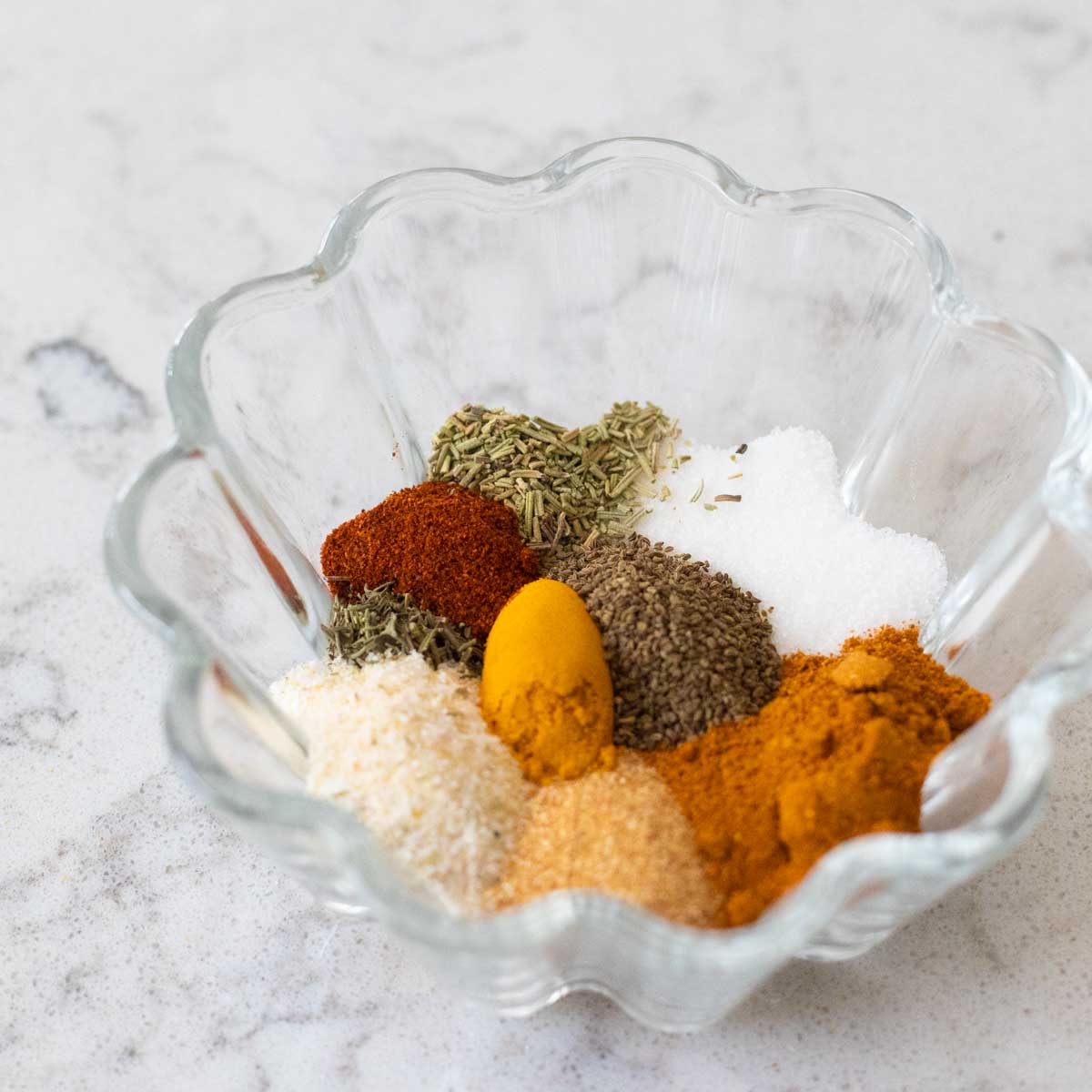 The spices to make the seasoned salt are in a small bowl with ruffled edges.