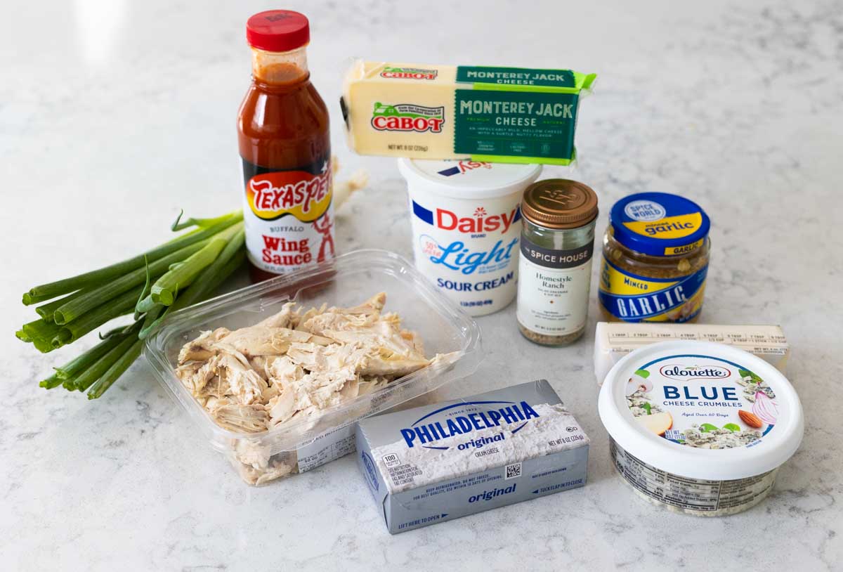 The ingredients to make baked buffalo chicken dip are on the counter.