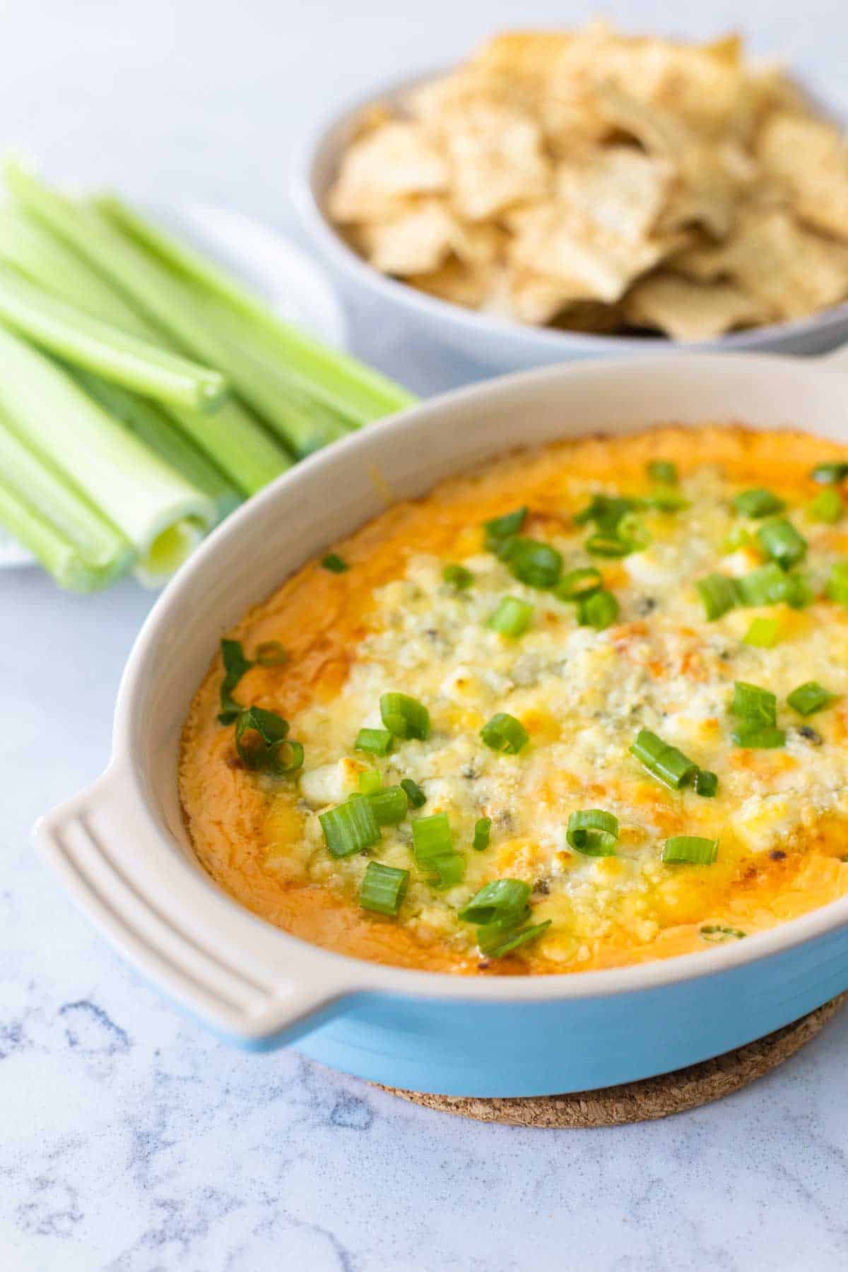 The finished dip sits on the counter next to celery sticks and tortilla chips.