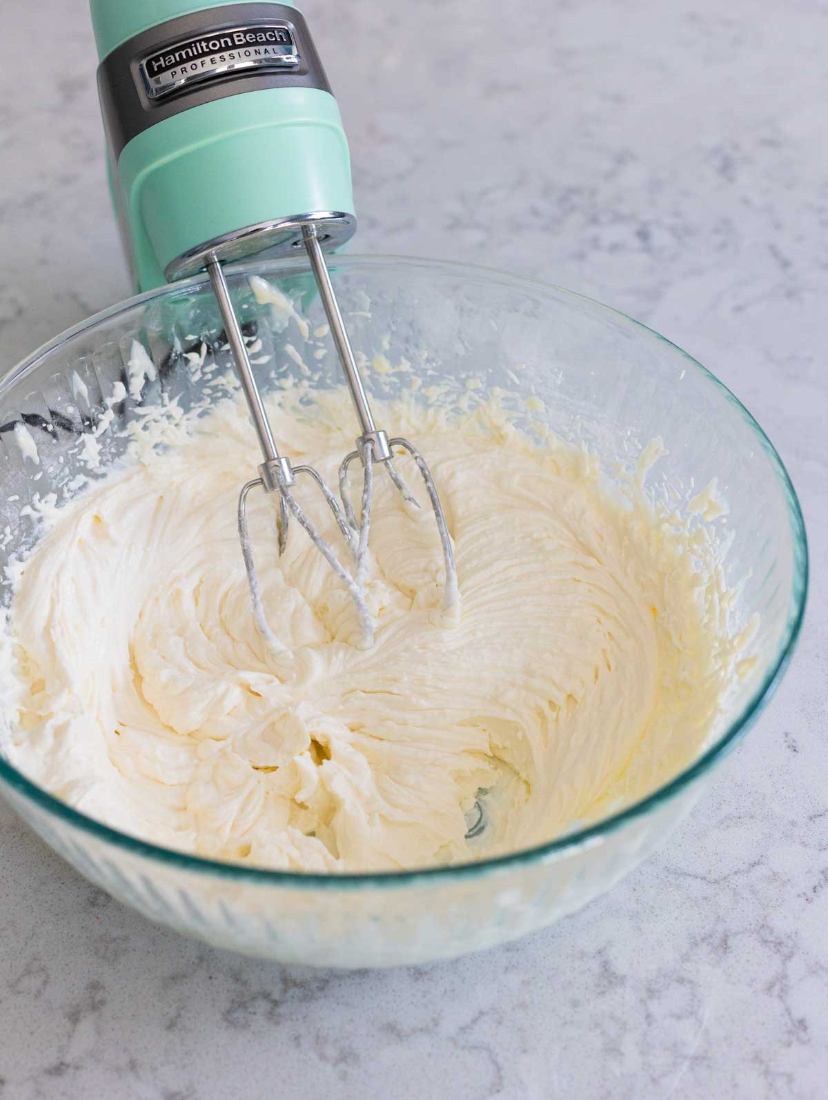 The hand mixer has beaten the cheeses until smooth.