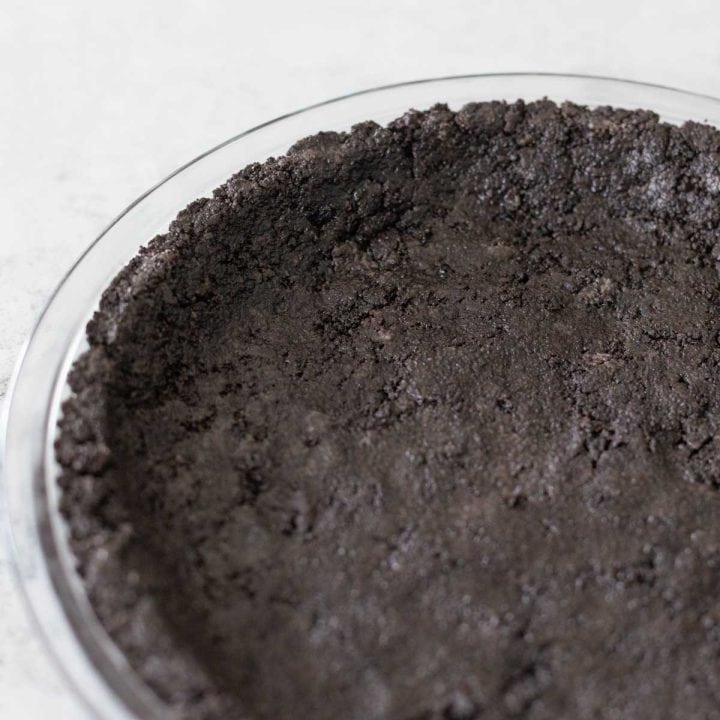 A clear pie plate is filled with the perfect Oreo cookie crust.