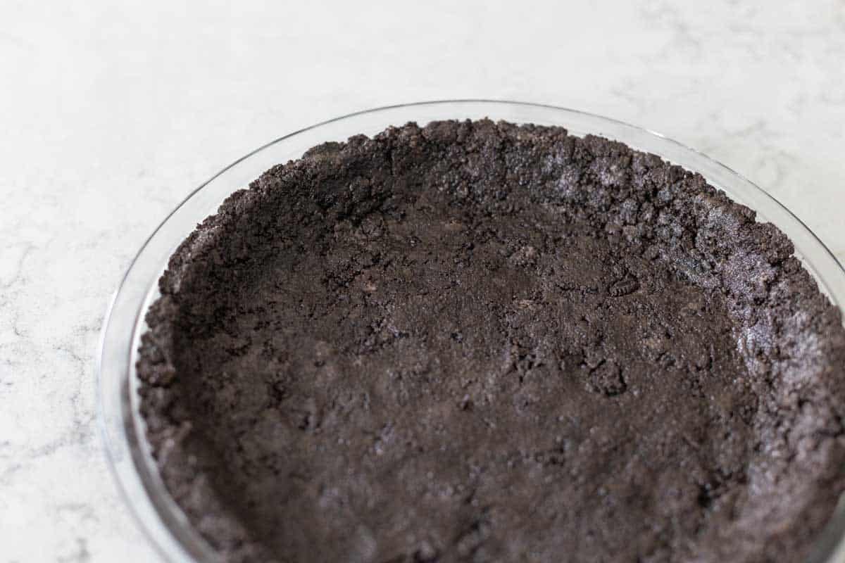 The cookie crust has been patted up the sides of the pie plate.